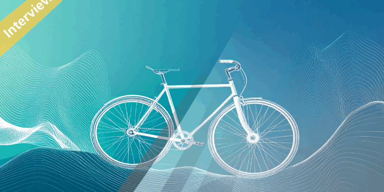 Eine Grafik eines Fahrrad vor einem blauen Farbverlauf. In der oberen rechten Ecke ist ein Banner mit der Aufschrift "Interview" zu lesen.